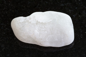 pebble of white marble on dark granite background