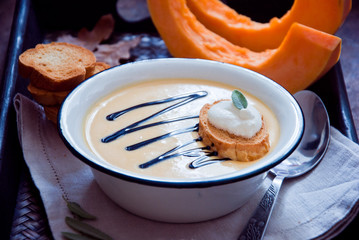 Homemade Pumpkin soup in a white plate and pieces of pumpkin