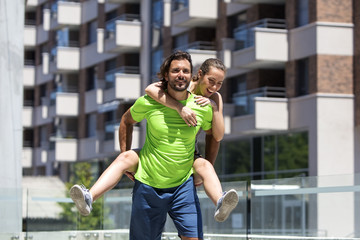 Sportsman holding sportswoman on his back outdoor