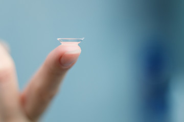 girl holds finger on a contact lens, closeup