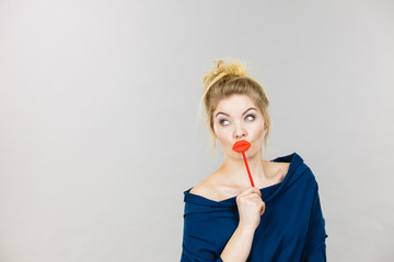 Funny woman holding big red lips on stick