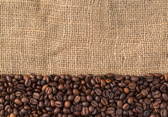 Coffee beans on natural jute background, top view.