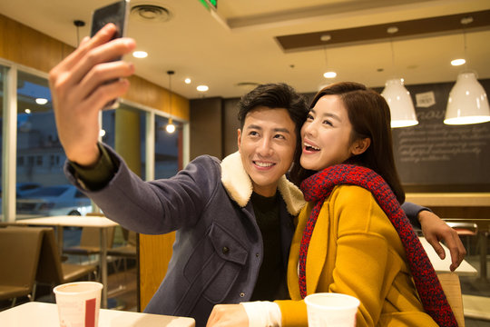 Happy young couple taking selfie in restaurant