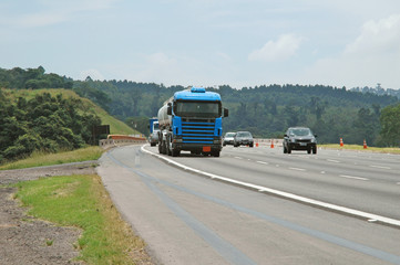 Fototapeta na wymiar no brand blue semi truck double tanker among the traffic on major higway