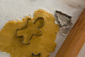 Gingerbread dough with flour, cookie cutter and rolling pin on