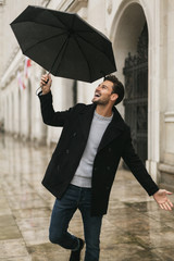 Handsome men dancing in the rain with an umbrella