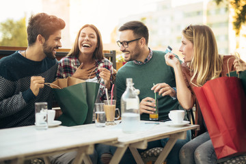 Group of four friends having fun a coffee together after shopping