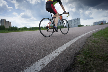Obraz premium Cyclist racing on the asphalt road at the summer day. blue sky with white clouds