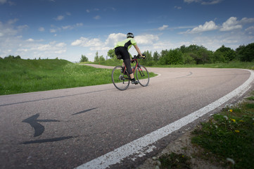 Cyclist racing on the asphalt road at the summer day. blue sky with white clouds
