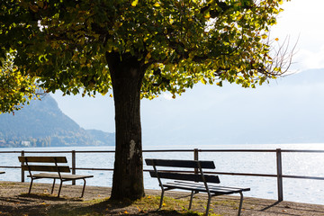 Fototapeta na wymiar Old wooden bench near the coast of a mountain lake.