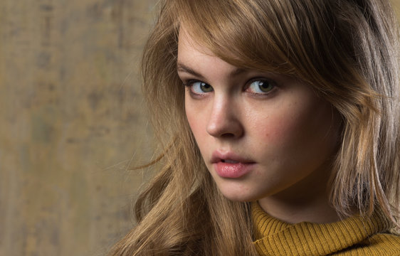 A beautiful young model in a mustard sweater. An image in beige tones.