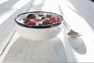 Healthy homemade  yoghurt  with fresh blueberries, raspberries and blackberries  with early summer morning light, shallow depth of field