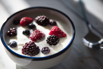 Healthy homemade  yoghurt  with fresh blueberries, raspberries and blackberries  with early summer morning light, shallow depth of field