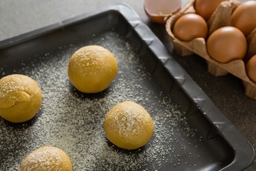 Dough balls with icing sugar on baking tray