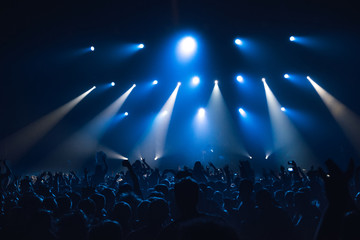 silhouettes of concert crowd in front of bright stage lights