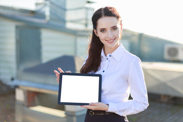 Attractive businesslady in white blouse and black skirt stand on the roof and hold tablet