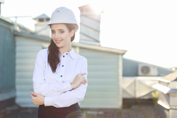 Attractive businesslady in white blouse, helmet and black skirt stand on the roof