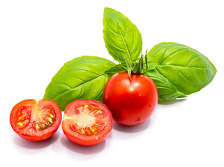 One whole red cherry tomato, two halves and fresh basil leaves isolated on white background
