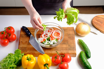 Woman put fresh green lettuce in a bowl, ingredients for salad