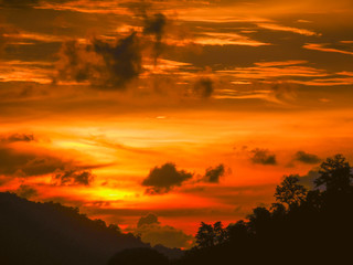 Twilight beautiful evening cloudy sky  after sunset background . There are silhouette mountains and trees.