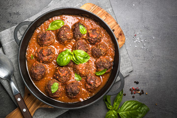 Meatballs in tomato sauce on a black background.