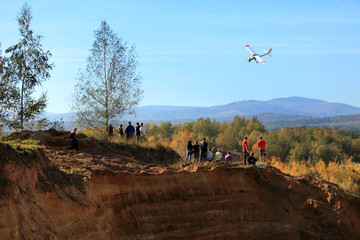 Samolot sterowany radiowo leci nad grupą ludzi w górach.