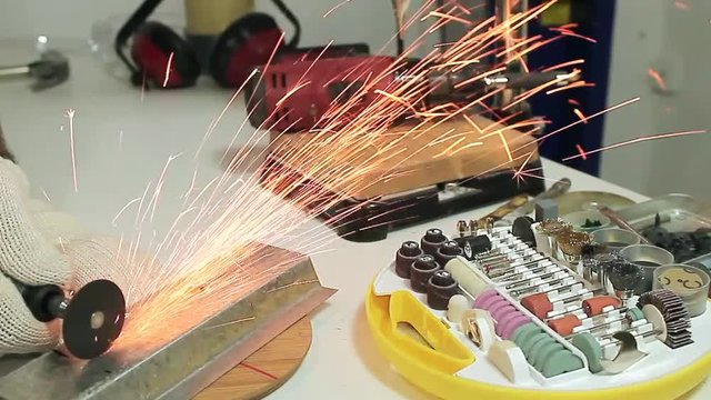 The worker is cutting the metal piece with multi tools in the workshop