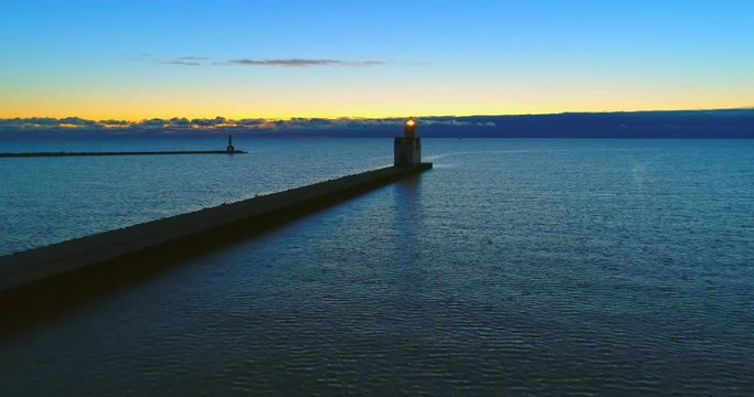 Lake Michigan Lighthouse shines a bright beacon into the vast twilight, aerial flyover. Lighthouses are symbolic of safety, welcome and hope.