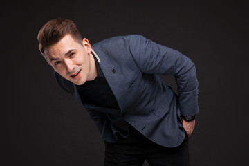 Fototapeta premium Handsome serious businessman in grey jacket, costly watch and black shirt, black background