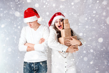 Happy couple man and fat woman celebrate Christmas and new year. Man and woman model plus size in santa hats. the girl XXL is happy with the New Year's gift, and the Guy is upset. with snowfall