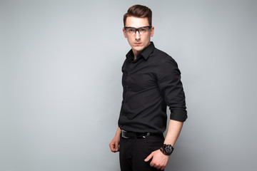 Obraz premium Attractive young businessman in costly watch, glasses and black shirt