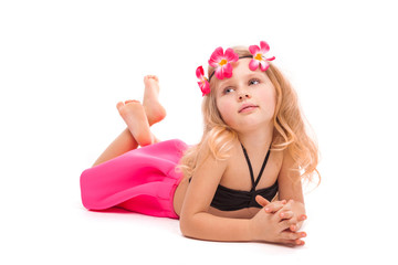 Obraz na płótnie Canvas Attractive little girl in black bikini, pink skirt and pink wreath, lies