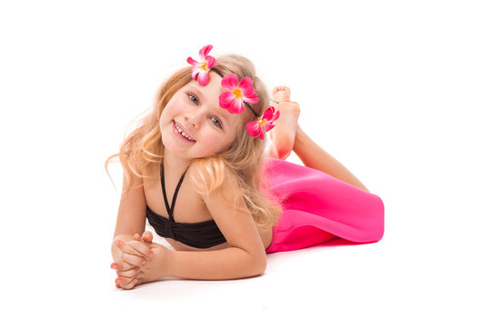 Attractive little girl in black bikini, pink skirt and pink wreath, lies