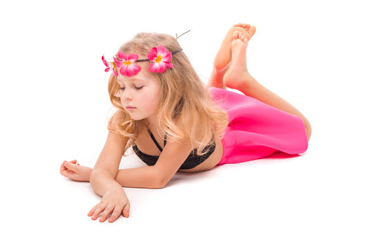 Attractive little girl in black bikini, pink skirt and pink wreath, lies
