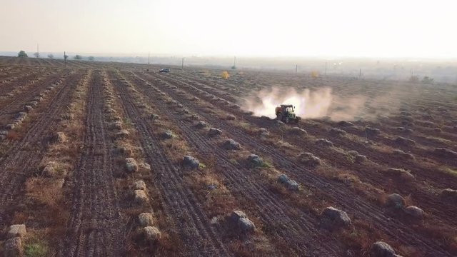 Aerial tractor sprinkles chemical fertilizers on the field of walnut and hazelnut farm frontal view2