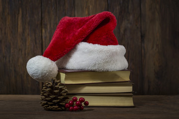 Obraz na płótnie Canvas Santa Claus hat, three books, fir cone, viburnum on a wooden background