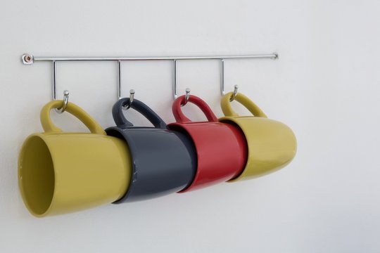Close-up of colorful mugs hanging on hook