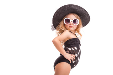 Attractive little girl in in black swimwear, white sunglasses and black hat