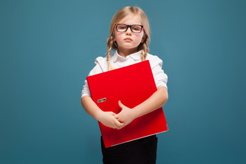 Pretty, cute little girl in white shirt, glasses and black trousers hold red paper folder