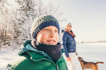Fototapeta na wymiar Father and son walk with dog in snow forest at sunny winter day
