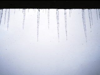 Icicles on the roof, winter sky, snowflakes