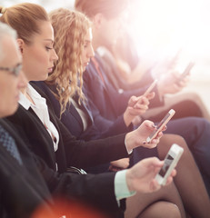 Businesspeople Using Technology In Busy Lobby Area Of Office