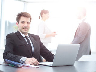 Fototapeta premium successful businessman sitting behind a Desk with an open laptop