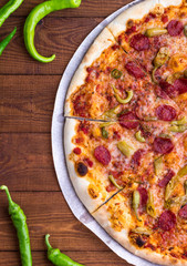 Tasty traditional italian pepperoni pizza on wooden table with chili. Wooden Background. Top view.