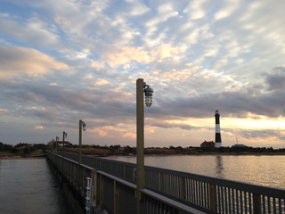 The Fire Island Lighthouse Against a Cloudy Sunset Sky Seen from a Pier on Great South Bay