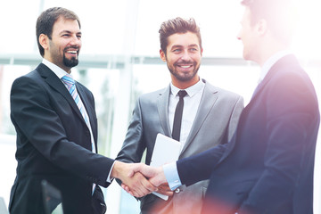 Fototapeta premium Mature businessman shaking hands to seal a deal with his partner and colleagues in a modern office
