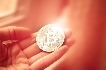 Coin bitcoin in the hands of the girl at the window. With blur and toning. The concept of crypto currency