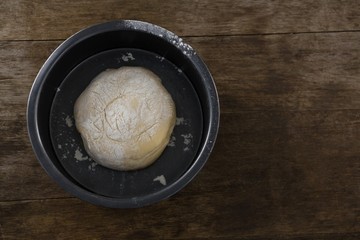 Kneaded dough placed in a bowl on a wooden table