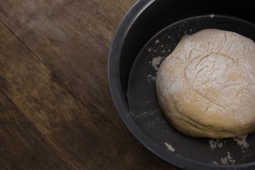 Kneaded dough placed in a bowl on a wooden table