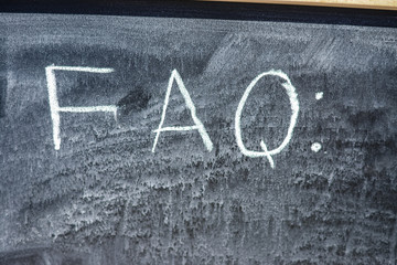 Child hand drawing FAQs - Frequently Asked Questions text on the blackboard. Education thoughts hot...